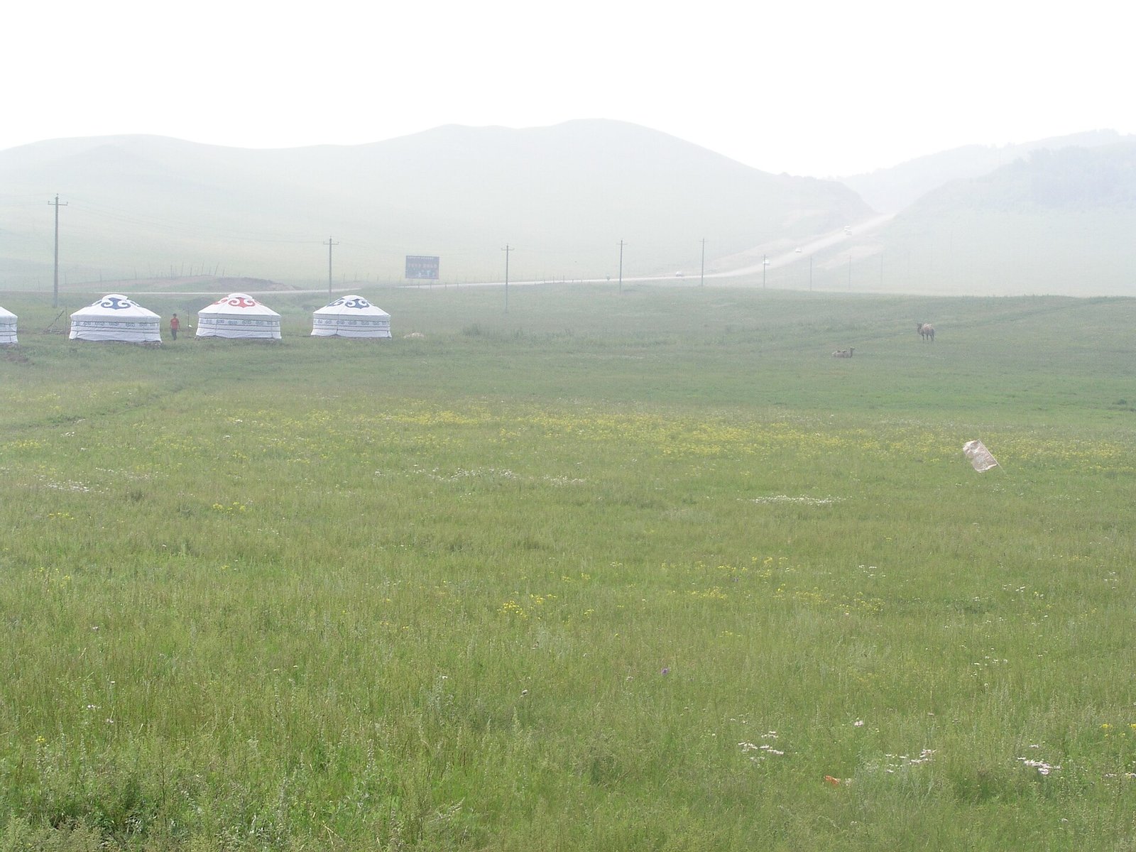 Yurts standing in mist on the grassland at Wulanbutong in Inner Mongolia, with hills fading behind