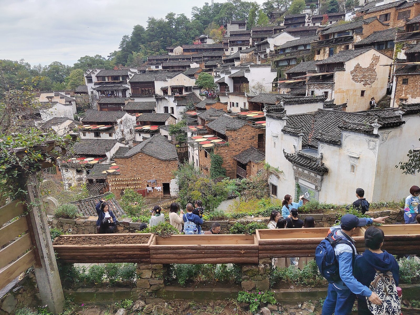 Bamboo trays of red chilli and orange produce drying on the tiled roofs of Huangling village