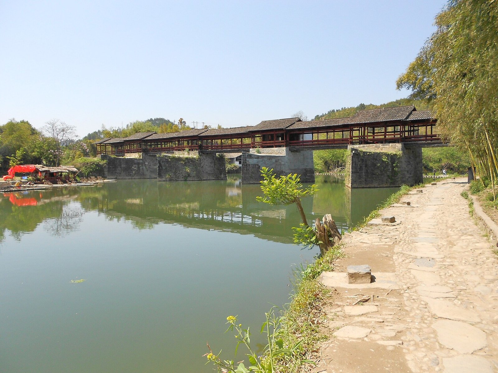 The covered wooden Rainbow Bridge at Qinghua in Wuyuan, reflected in the still water below