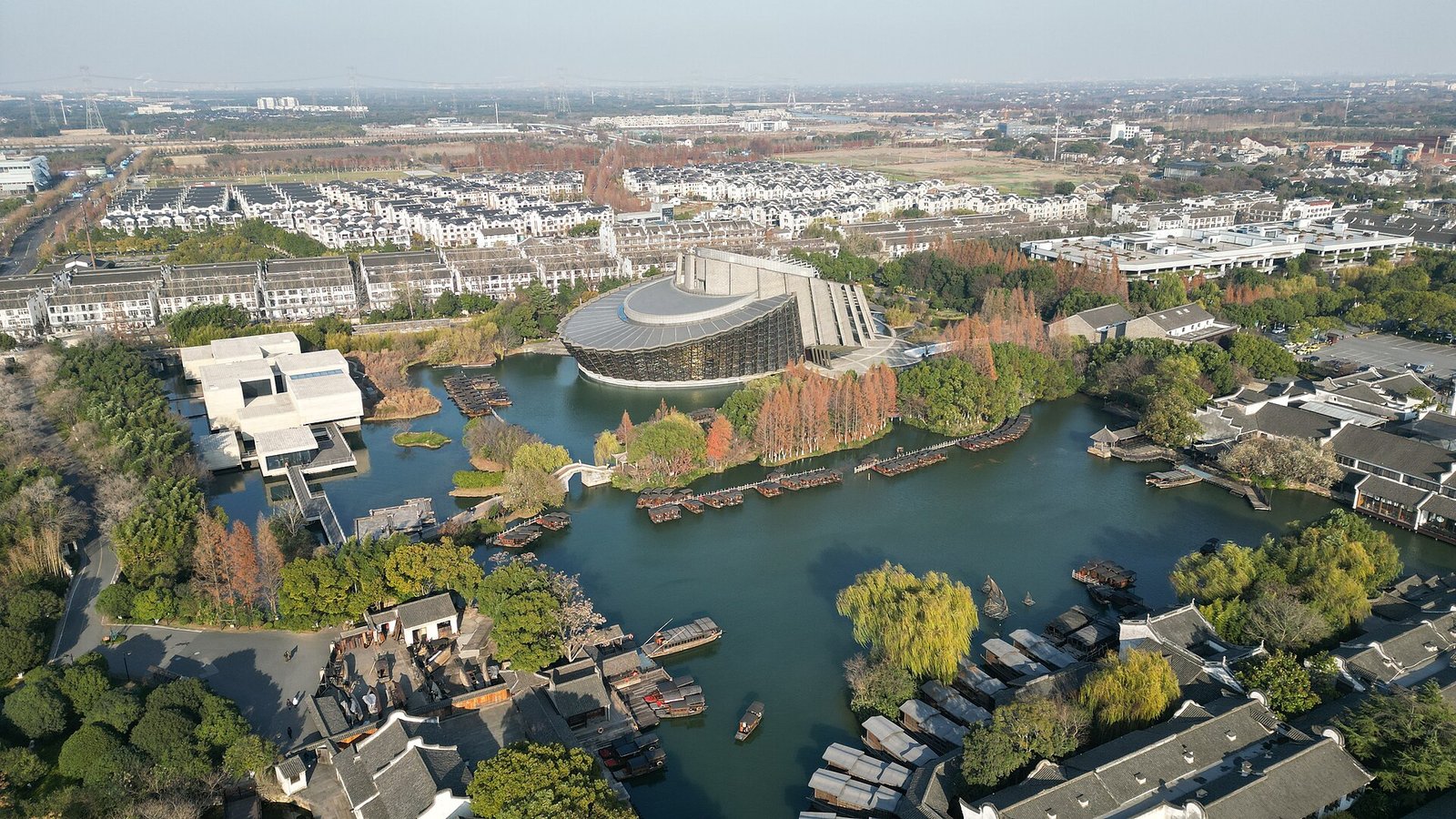 An aerial view of Wuzhen with the modern dark-roofed Wuzhen Theatre and the surrounding water town roofscape