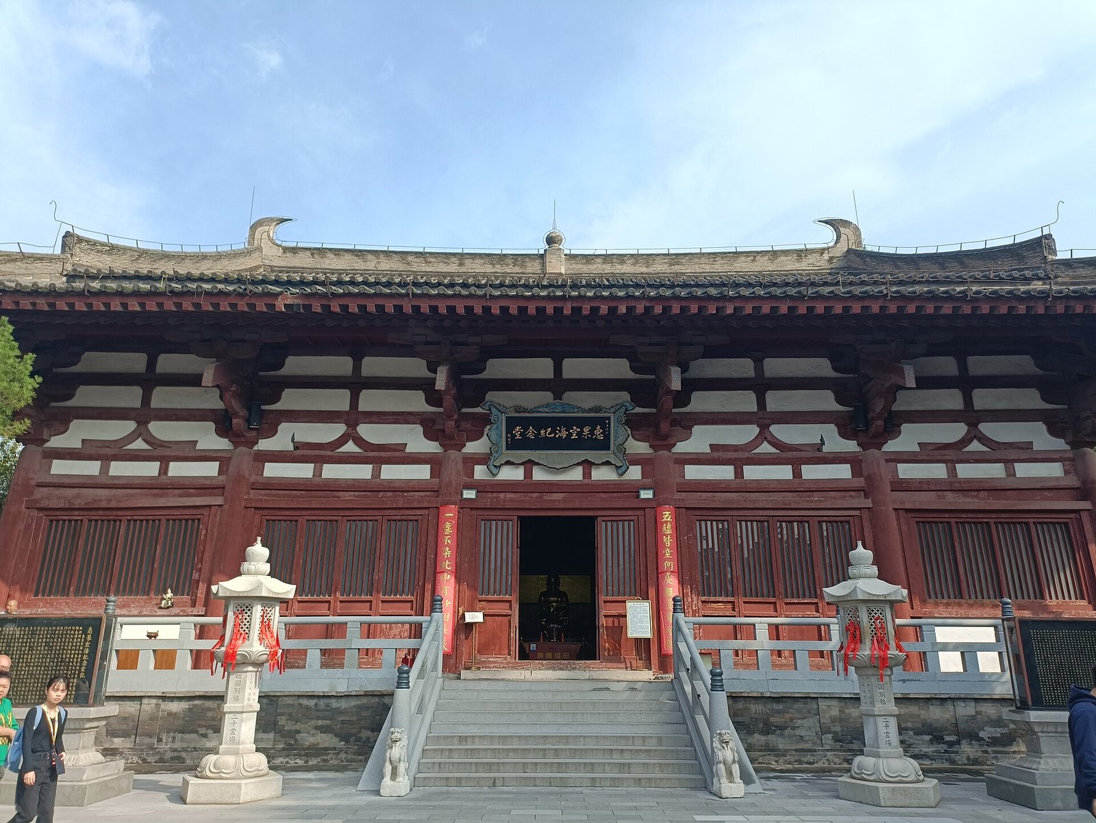 A red-and-white Tang-style Chinese temple hall with a carved plaque above its entrance