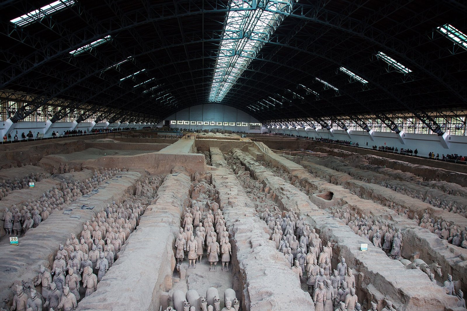 Rows of life-size ancient terracotta warrior figures in a large excavation pit