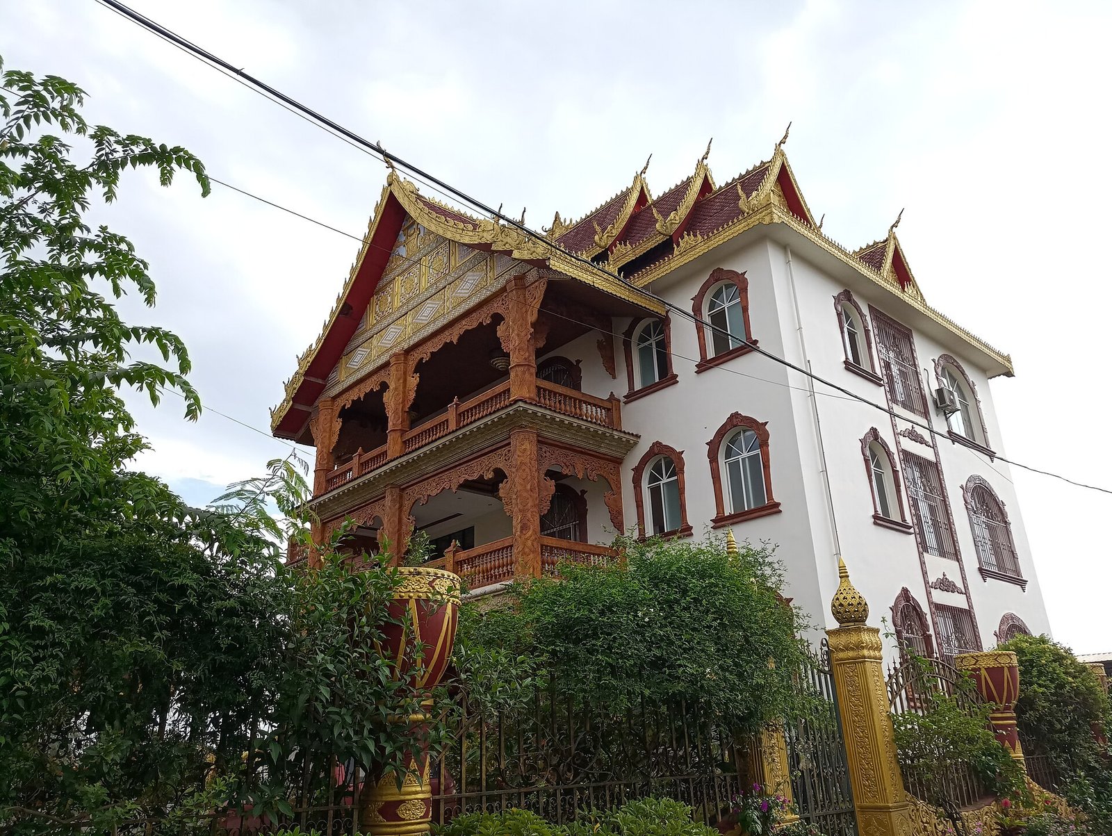 A traditional Dai stilt house with a steep tiled roof among palms and tropical greenery in Yunnan