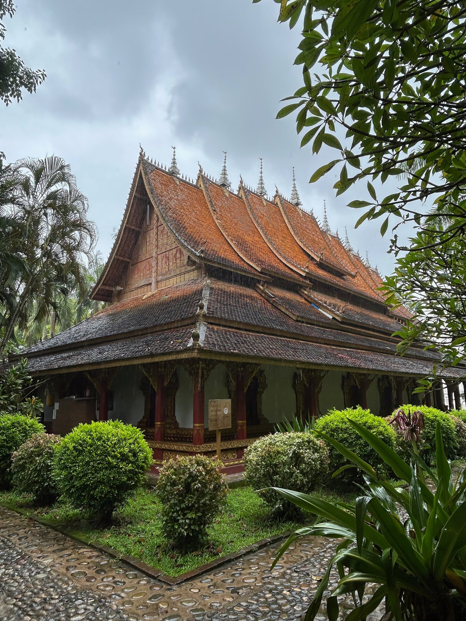 A golden Dai-style Buddhist pagoda in southern Yunnan, with tiered roofs against a tropical sky