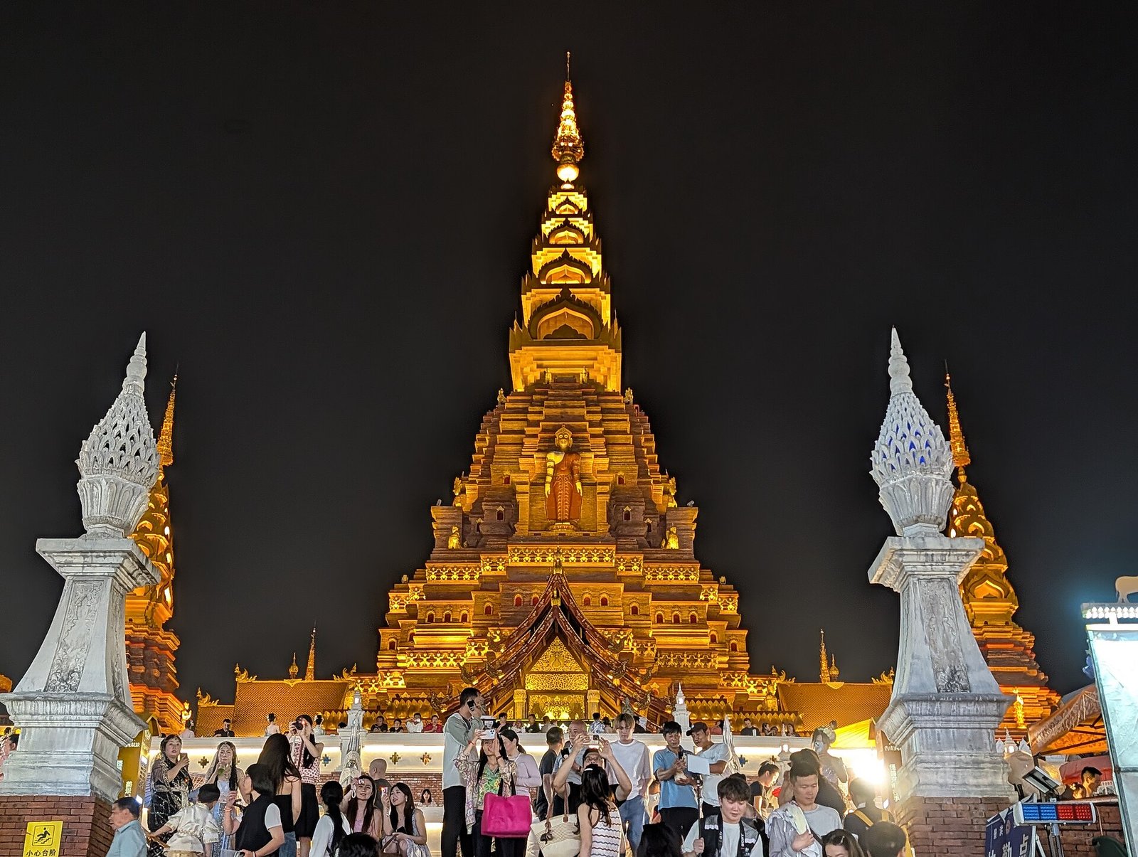 The golden pagoda of Gaozhuang in Jinghong lit up at night, with crowds and lanterns around it