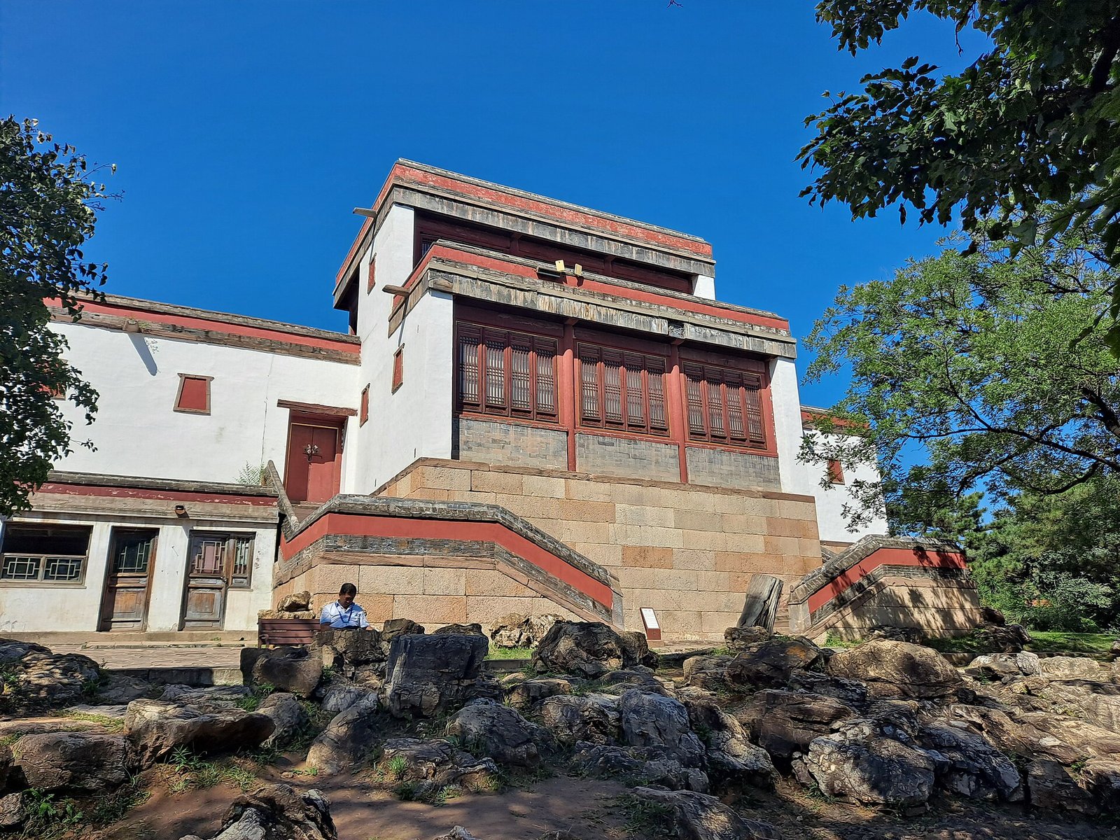 A white and red wall of Xumifushou Temple at Chengde with a golden roof behind it