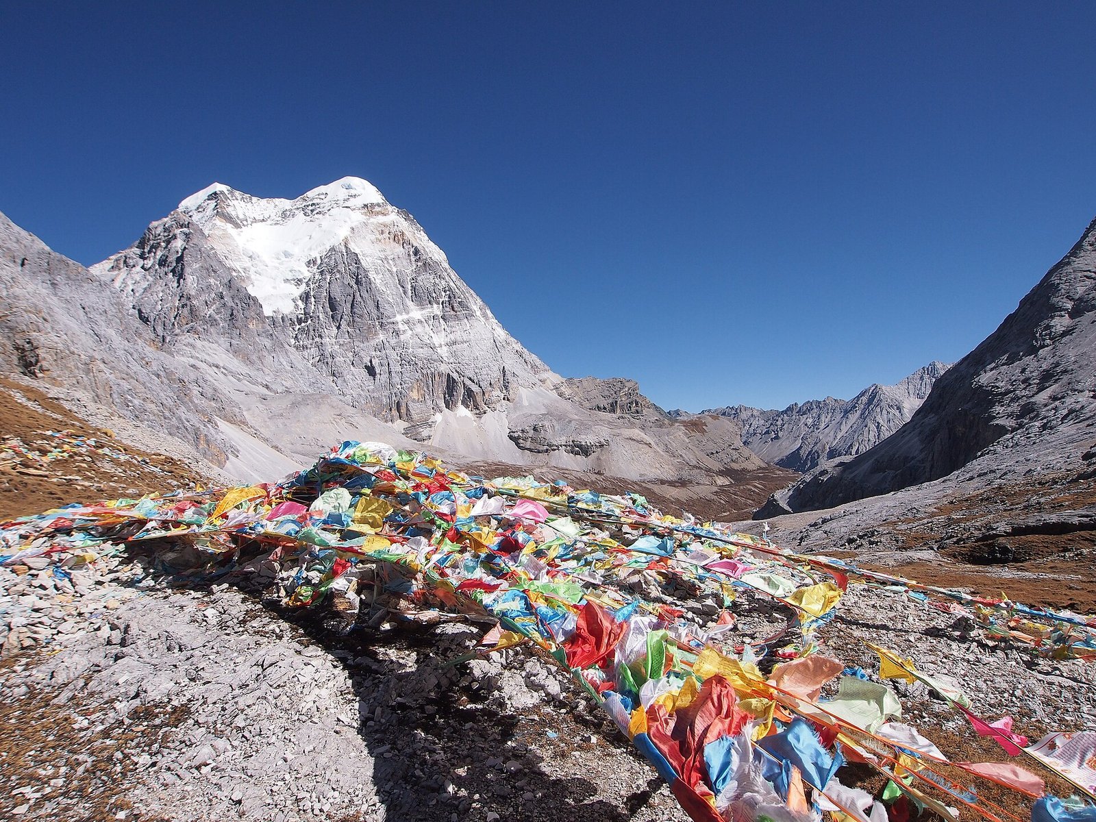 Prayer flags strung in front of the snow face of Chenresig at Yading