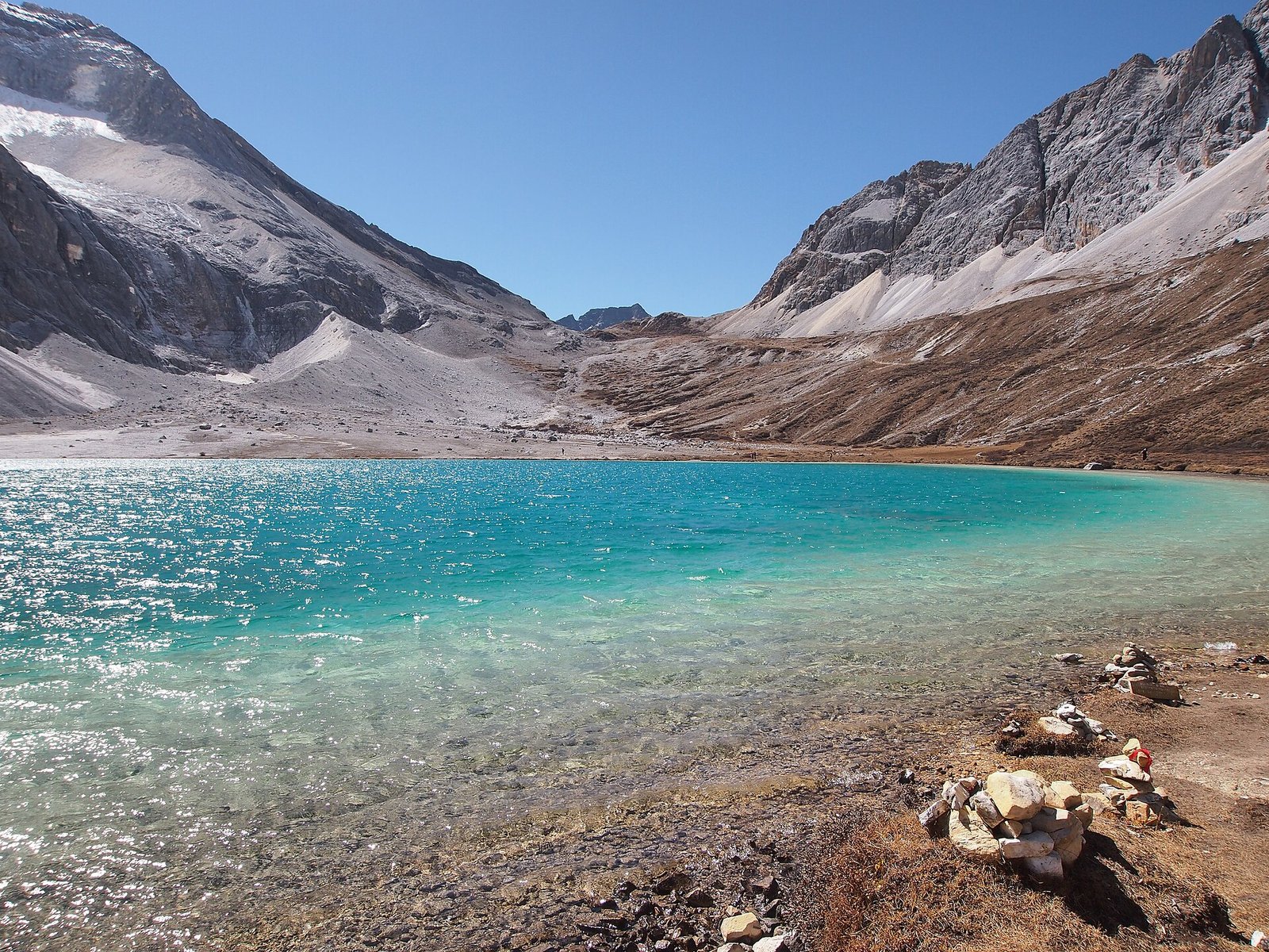 The turquoise glacial water of Milk Lake at Yading, ringed by pale rock and scree