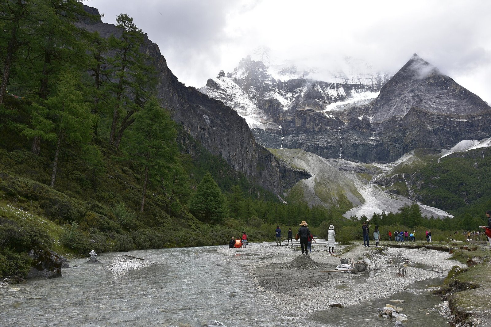 A braided river running through a green valley below two snow-covered peaks in the Yading nature reserve