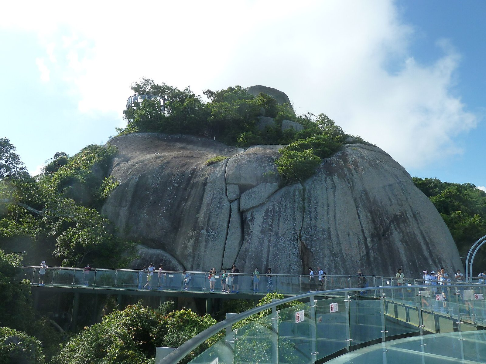 A large granite outcrop with a glass viewing platform cantilevered from its side above forested slopes
