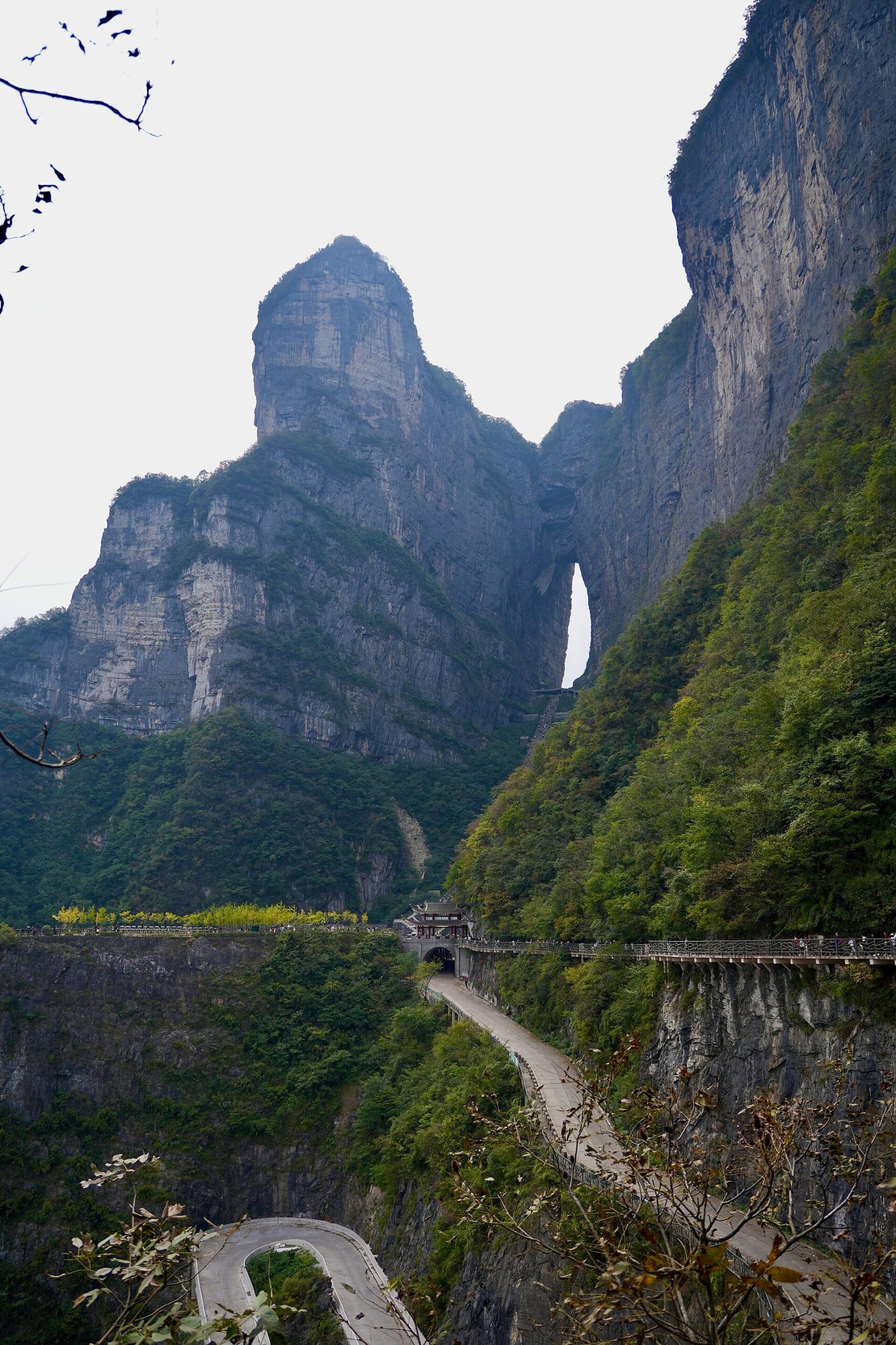 The natural arch of Tianmen Cave on Tianmen Mountain, with the 99-bend road below