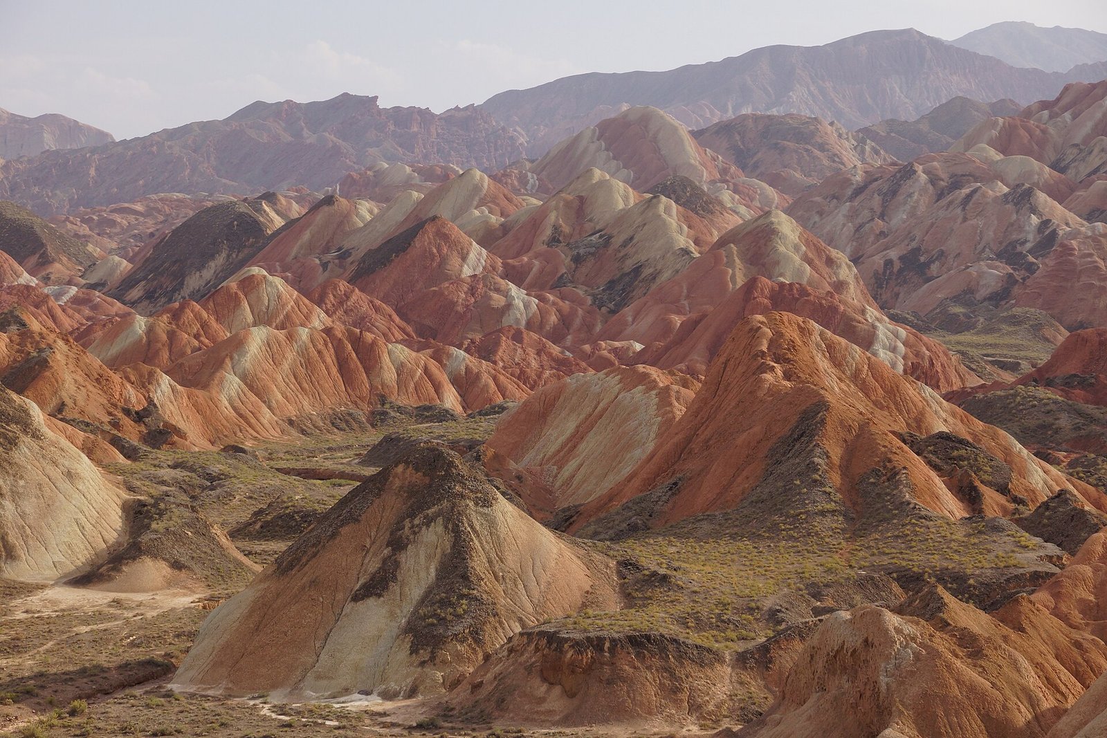 A wide panorama of banded hills at Zhangye National Geopark in Gansu, with ridges receding into haze