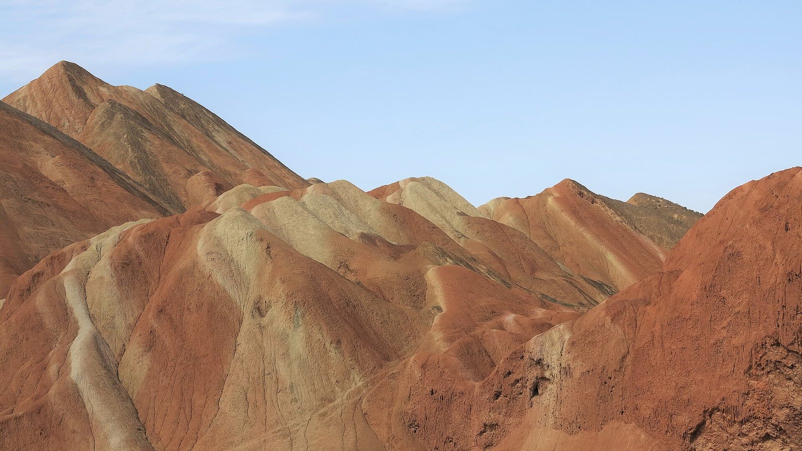 Low rounded ochre and pale banded hills at Zhangye Danxia, with soft shoulders and no cliff faces