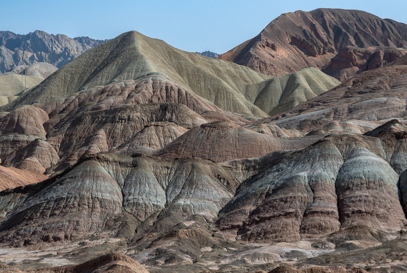 Strongly folded and tilted coloured strata at Zhangye Danxia, showing red, grey and buff layers in diagonal bands
