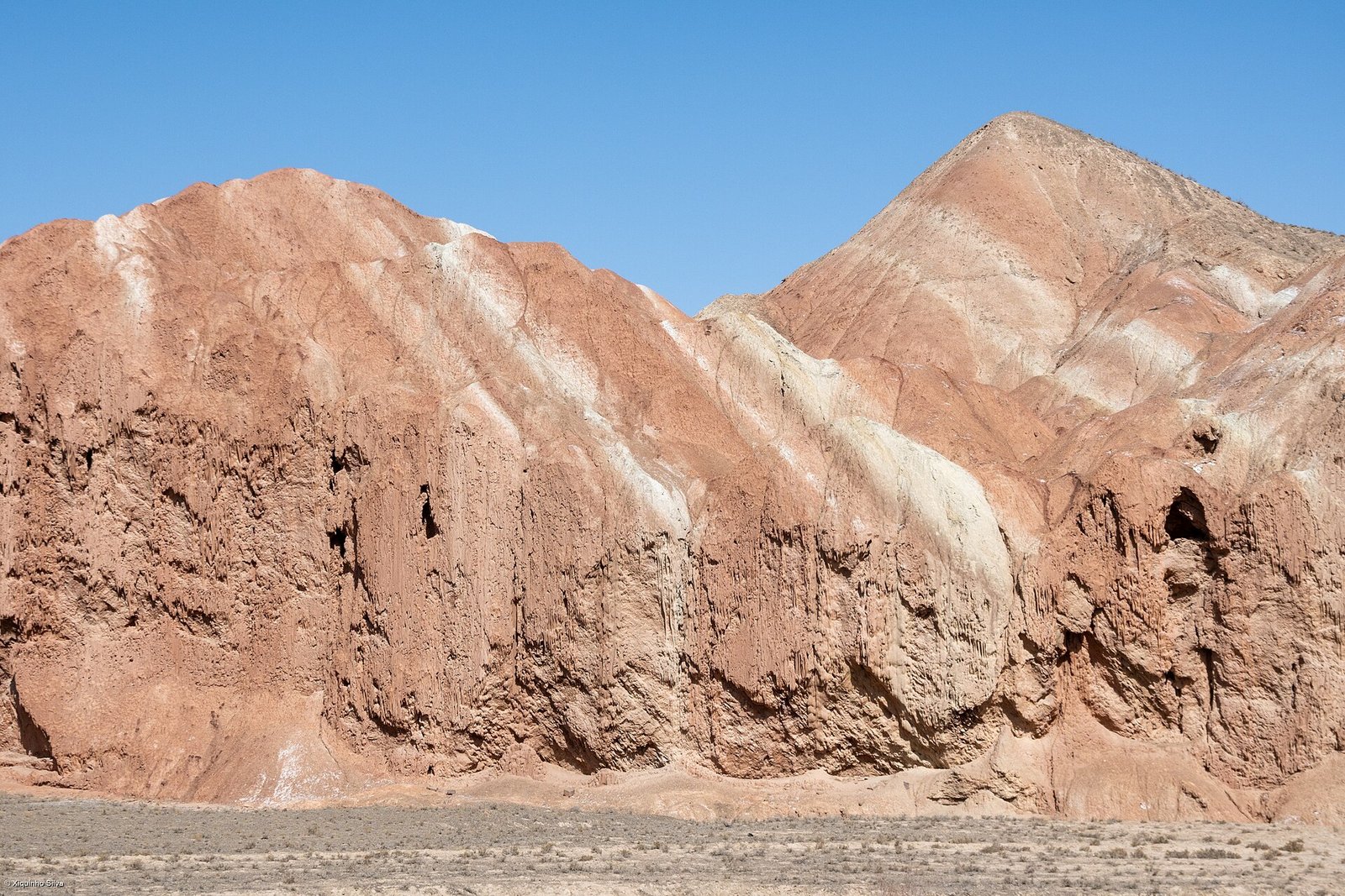 A close view of thin alternating red, pink and pale bands in the rock at Zhangye Danxia