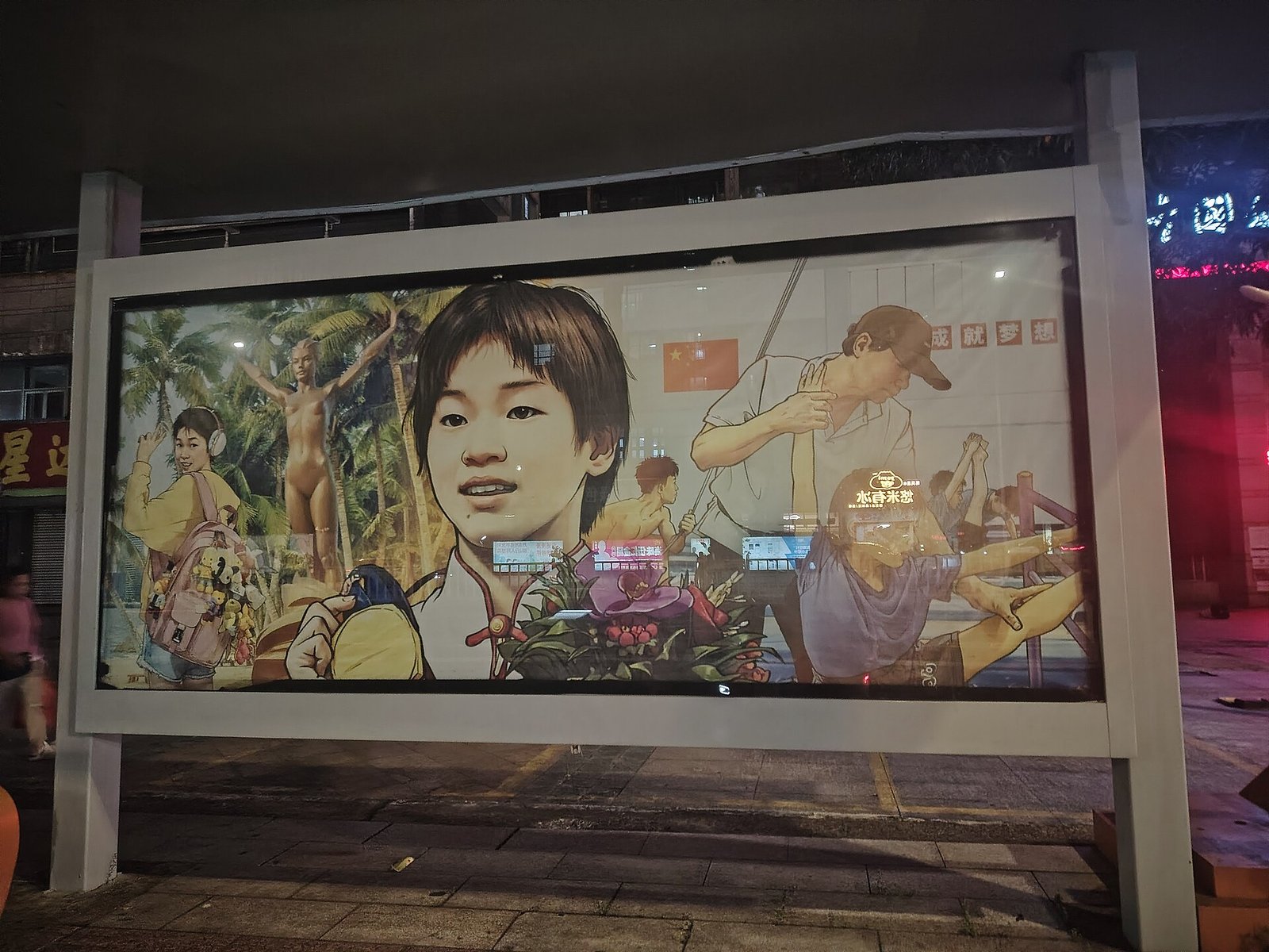 A large illuminated panel at a bus stop at night showing a painted mural of a young diver in various poses with palm trees and a Chinese flag