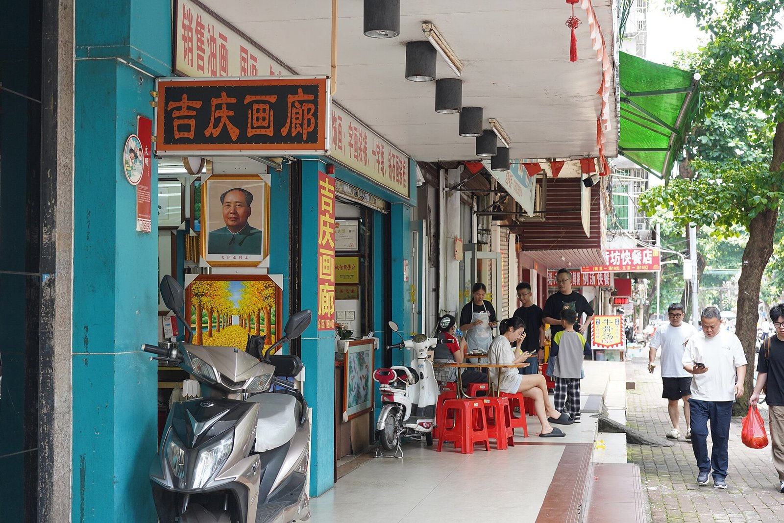A street in Xiashan district with a painted portrait of Mao Zedong on a building facade above shuttered shops, photographed in 2026