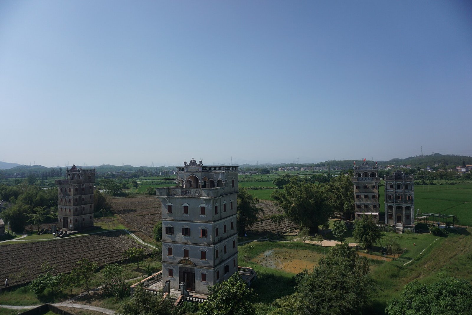 Several fortified towers of different heights rising among trees and fields in Zili Village